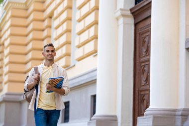 Üniversite öğrencisi. Sırt çantalı, kısa saçlı, gülümseyen öğrenci.