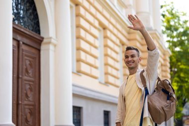 Neşeli öğrenci. Elinde defterle gülümseyen genç adam neşeli görünüyor.
