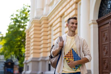 Neşeli öğrenci. Elinde defterle gülümseyen genç adam neşeli görünüyor.