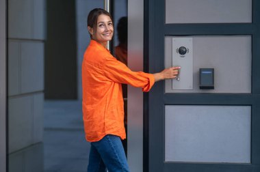 Modern tuş takımı sistemini kullanan bir kadın, ev güvenliği önceliklerine erişimi kontrol etmeyi sürdürüyor.