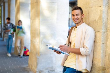 Öğrenci. Adam duvarın yanında duruyor ve bir şeyler yazıyor.