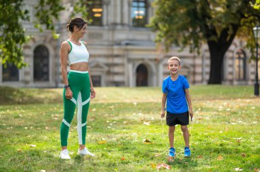 Antrenman yapıyorum. Formda bir kadın ve oğlu parkta egzersiz yapıyor.