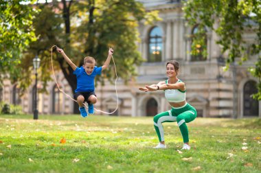 Antrenman yapıyorum. Formda bir kadın ve oğlu parkta egzersiz yapıyor.