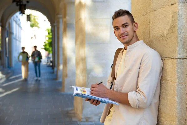 Öğrenci Duvarın Yanında Elinde Kitapla Duran Yakışıklı Genç Adam — Stok fotoğraf