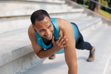Antrenman yapıyorum. Esmer tenli sporcu egzersiz yapıyor ve halinden memnun görünüyor.