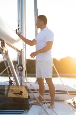 Yolculuk. Beyaz tişörtlü yakışıklı adam yatta bir şeyler yapıyor.