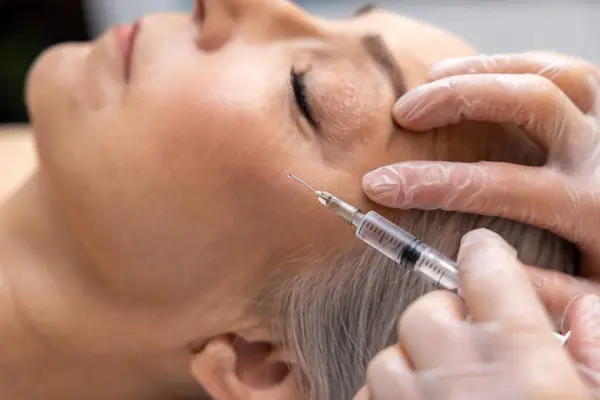 Anti age procedures. Woman having anti wrinkle filler injections to eye area