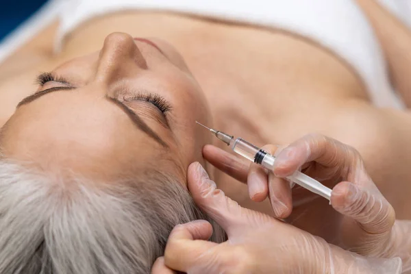 Anti age procedures. Woman having anti wrinkle filler injections to eye area