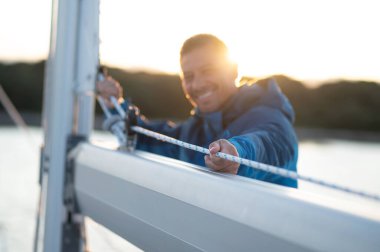 Yattaki adam. Olgun bir adam yatta yelken açıyor ve meşgul görünüyor.