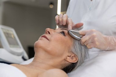 Mikro akım tedavisi. Olgun bir kadın güzellik kliniğinde mikro tedavi görüyor.