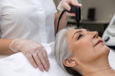 Lazer prosedürleri. Güzellik uzmanı bir kadına lazer güzellik prosedürü uyguluyor.