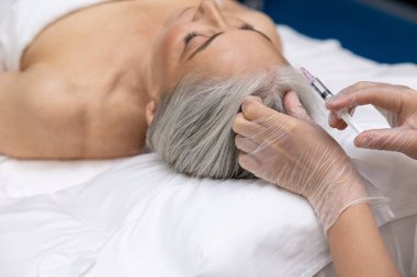 Güzellik tedavisi. Olgun kadın güzellik kliniğinde enjeksiyon yaptırıyor.
