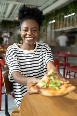 Tatlı, koyu tenli, pizza yiyen ve iyi hisseden bir kadın.