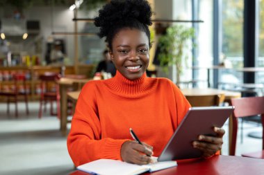 Positive young dark-skinned woman in orange roll-neck sweater clipart