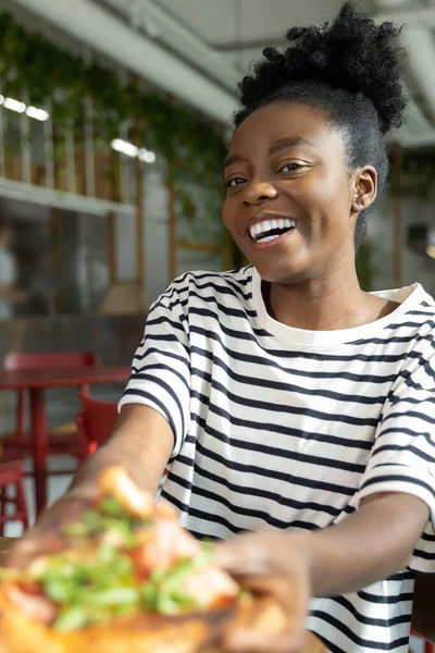 Tatlı, koyu tenli, pizza yiyen ve iyi hisseden bir kadın.