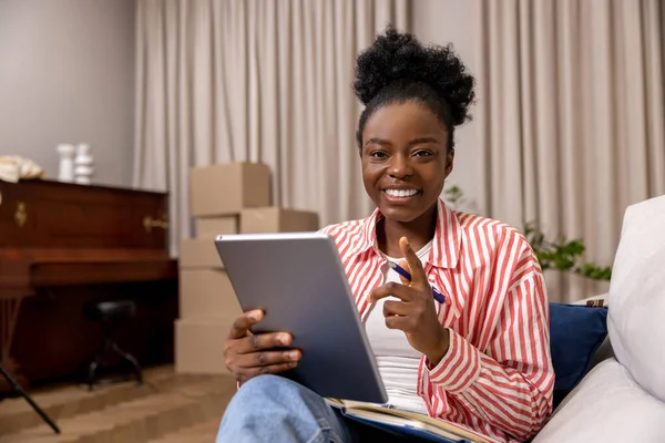 积极快乐的女性在搬迁后 坐在家里看电子书 边做笔记 — 图库照片