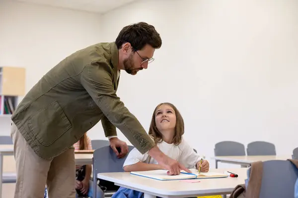 Adult man teacher helping pupils during lesson in school.