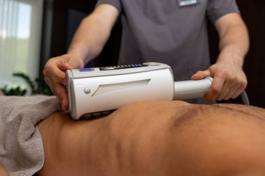 Vücut bakımı prosedürleri. Genç siyah saçlı adam klinikte tıbbi prosedür uyguluyor.