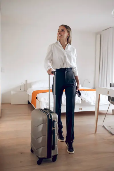 Blonde woman in her own or rented flat with suitcase moving to new apartment.