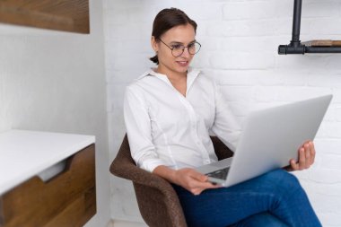 Dizüstü bilgisayarda çalışan kendine güvenen genç bir kadın..