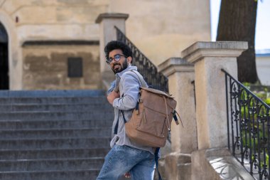 Turist. Genç, uzun boylu Hindu adam eski bir binanın merdivenlerinde dikiliyor.