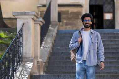 Turist. Genç, uzun boylu Hindu adam eski bir binanın merdivenlerinde dikiliyor.