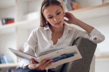 Sarışın kadın evde dinleniyor. Modern ev içi kitap okuyor..