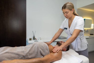 Masaj salonunda. Genç bir adam masaj salonunda rahatlatıcı prosedürler uyguluyor.