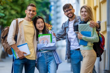 Kampüste dikilen neşeli, çok kültürlü üniversite öğrencileri ya da arkadaşlar..