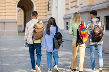 Bir grup öğrenci, derslerden sonra kampüste sırt çantalarıyla gezip derslere gidiyorlar..
