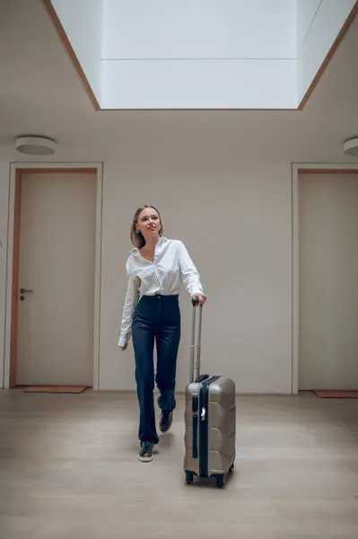 In a hotel. Young elegant woman with a suitcase in a hotel hall