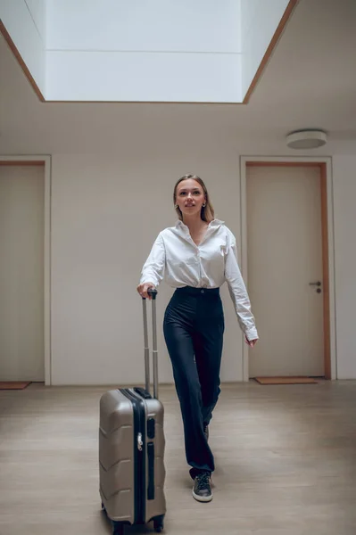 In a hotel. Young elegant woman with a suitcase in a hotel hall