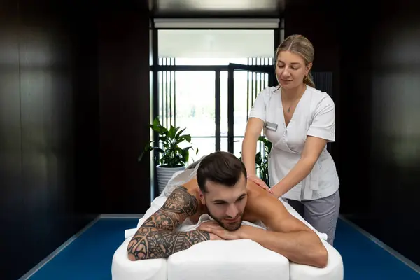 Massage salon. Man having back massage session and looking contented