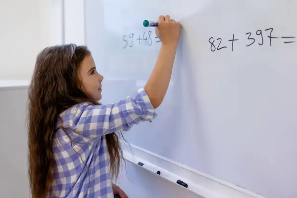 学校のホワイトボードの数学方程式を数える小さな女子高生 — ストック写真