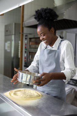 Pizzacı esmer kadın pizza pişiriyor.