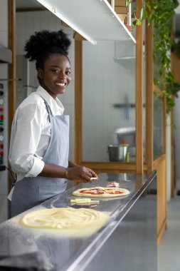 Kadın pizzacı aşçı mutfakta pizza hazırlıyor.