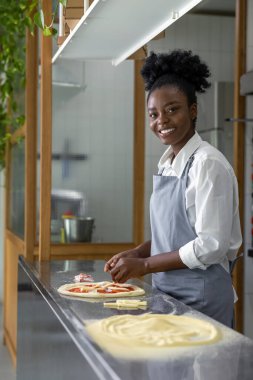 Koyu tenli kadın pizza için hamur hazırlıyor.
