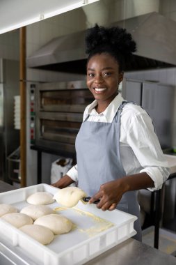 Gülümseyen Afrikalı Amerikalı kadın masanın yanında pizza için mangır ile duruyor.