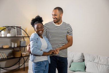 Mutlu, güler yüzlü bir çift evde dikilirken birbirlerine sarılıyorlar.