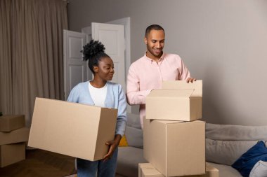 Mutlu bir adam ve kadın yeni bir eve taşınıyor. Elinde karton kutular, içinde eşyalar var.