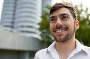 Keyfin yerinde. Koyu renk saçlı, beyaz gömlekli genç adam gülümsüyor.