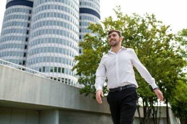 Keyfin yerinde. Siyah saçlı, beyaz gömlekli, gülümseyen ve neşeli hisseden genç bir adam.