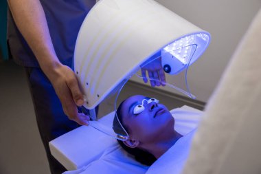 Fototerapi. Fototerapi seansı sırasında bir hastayla çalışan bir tıp uzmanı.