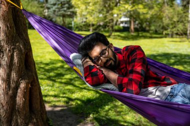 Hamaktaki adam rahatlamış ve dinlenmiş hissediyor.