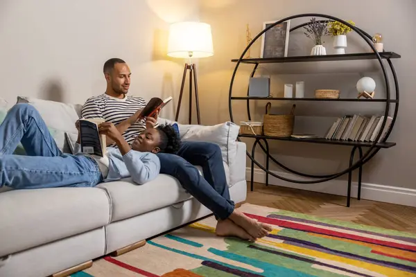 Calm man and woman reading books on couch in home interior at home