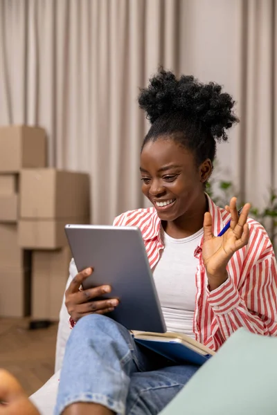 拥有非洲式发型的快乐女人坐在沙发上 通过数码平板电脑进行视频通话 — 图库照片