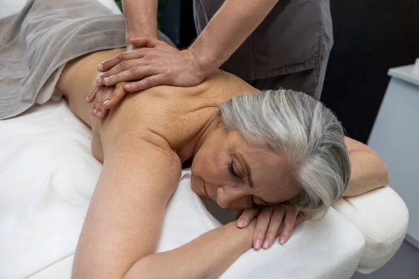 Massage Dos Femme Mûre Aux Cheveux Gris Allongée Sur Canapé — Photo