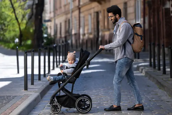 Dad. Dark-haired tall man with a baby carriage in the city street