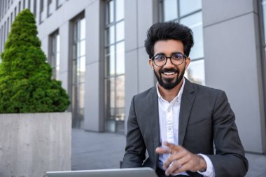 İş adamı ofis binasının yakınında dizüstü bilgisayarda çalışıyor.