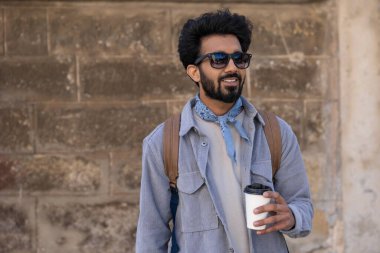 Hindu adam. Elinde bir fincan kahveyle gülümseyen pozitif Hintli adam.